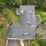 drone view of a new asphalt shingle roof in a green forest
