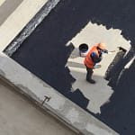 top view of worker applying the roof coating