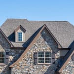 house with stone exterior and shingle roof