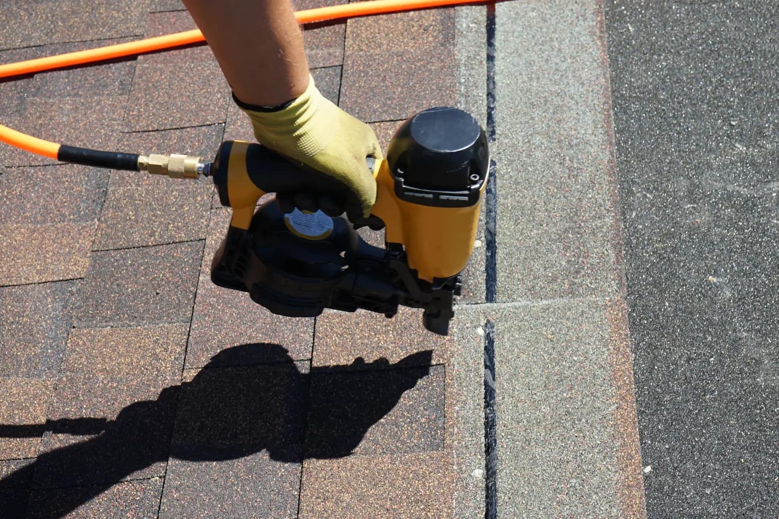 Closeup of Kitsap Roof Pros using nail gun to install roof shingles.