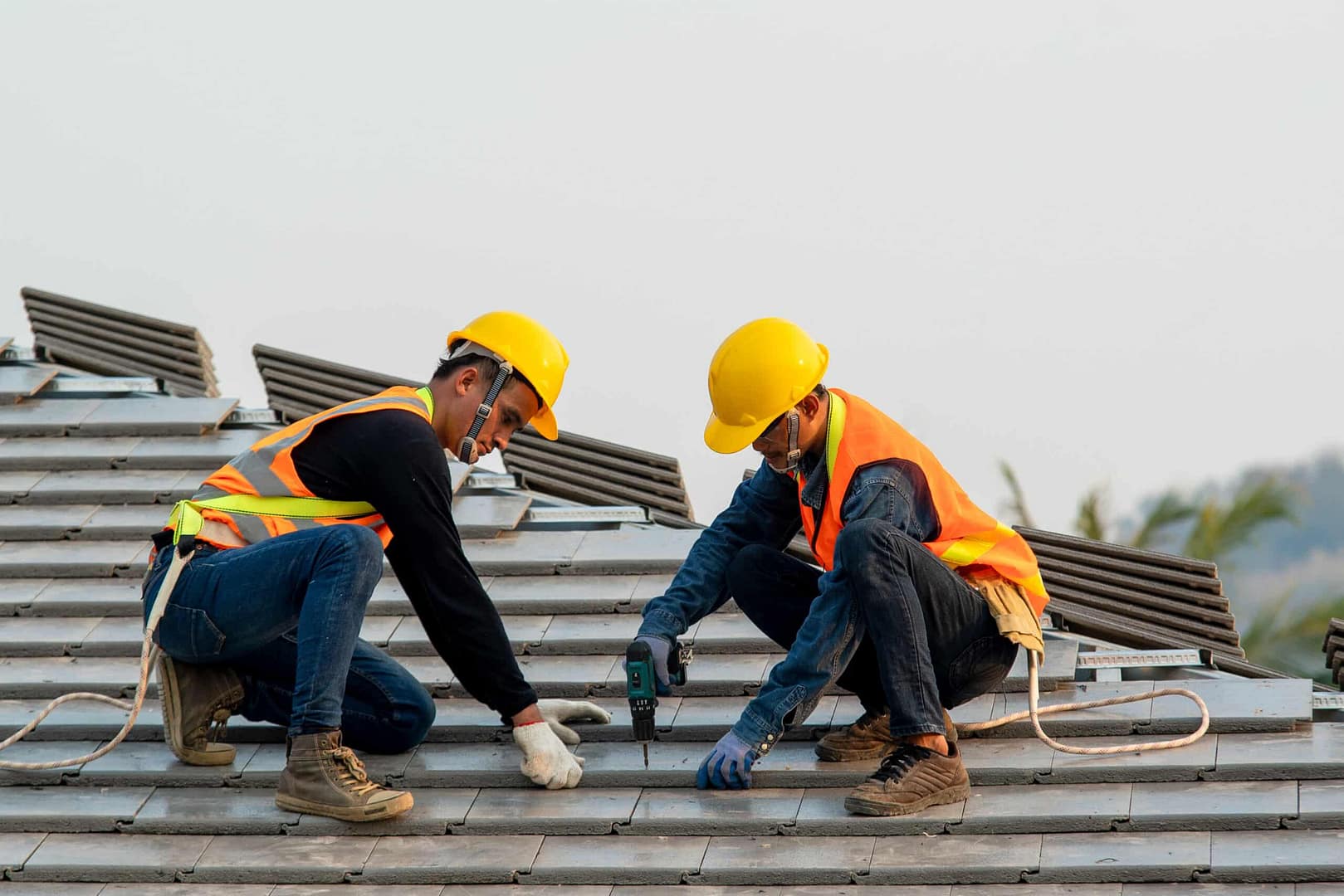 two professional workers installing roofing with drill