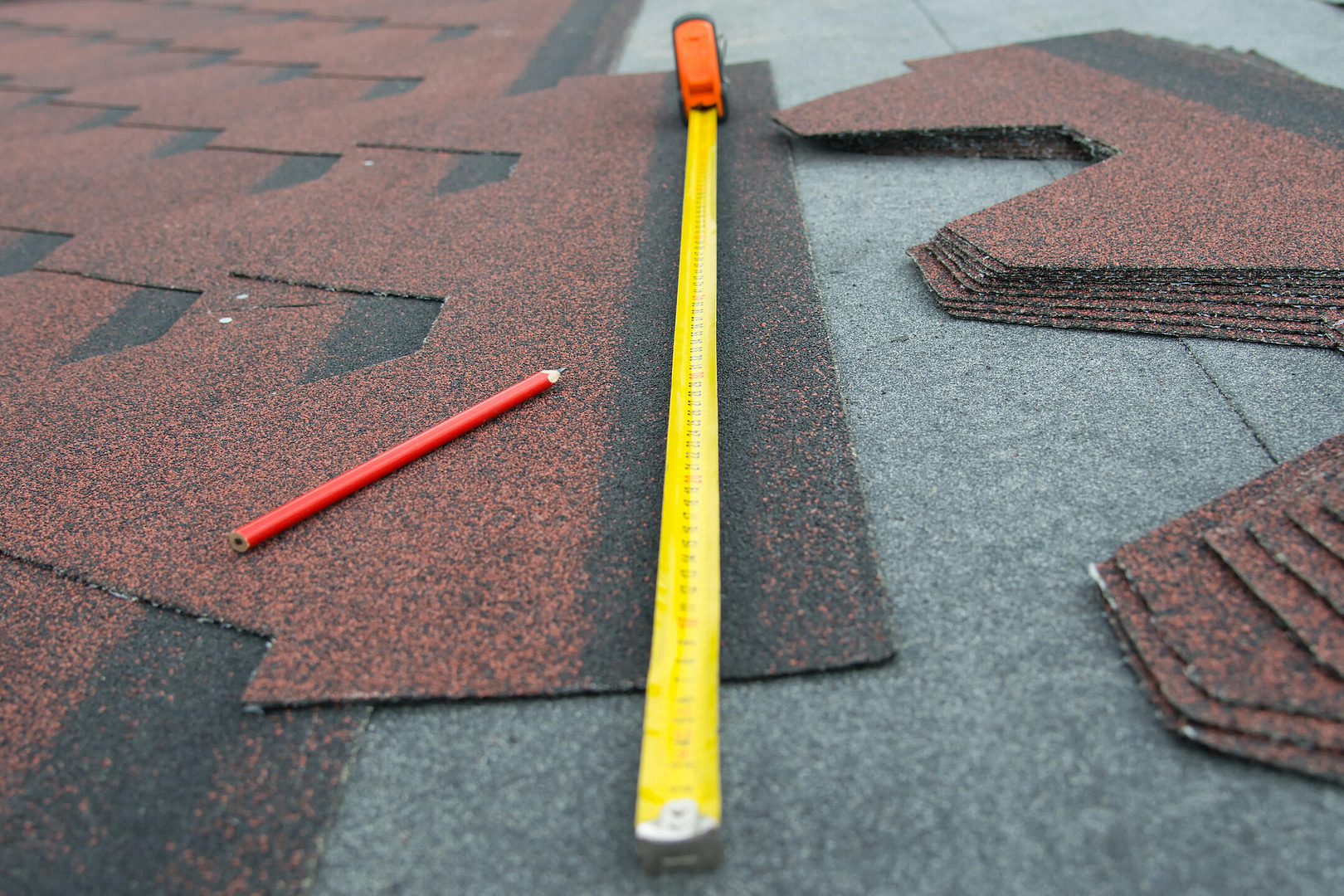 how to measure a roof for shingles-close up of tape measure, pencil, and shingles for roofing