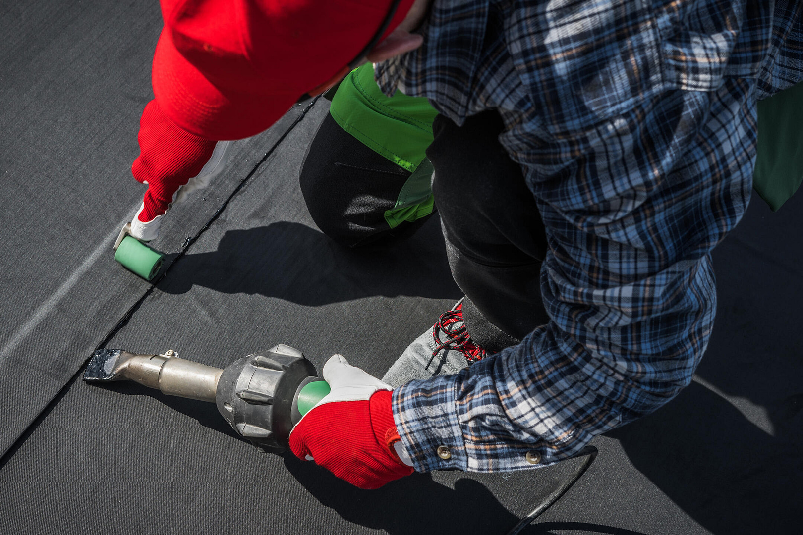 epdm roofing-over the shoulder view of tech using heat gun to install a section of epdm roofing material