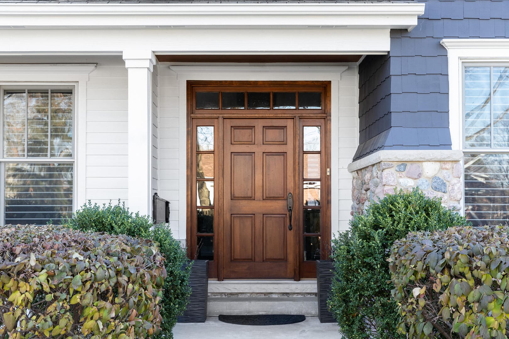 front door styles-wood front door on house with bushes in the foreground