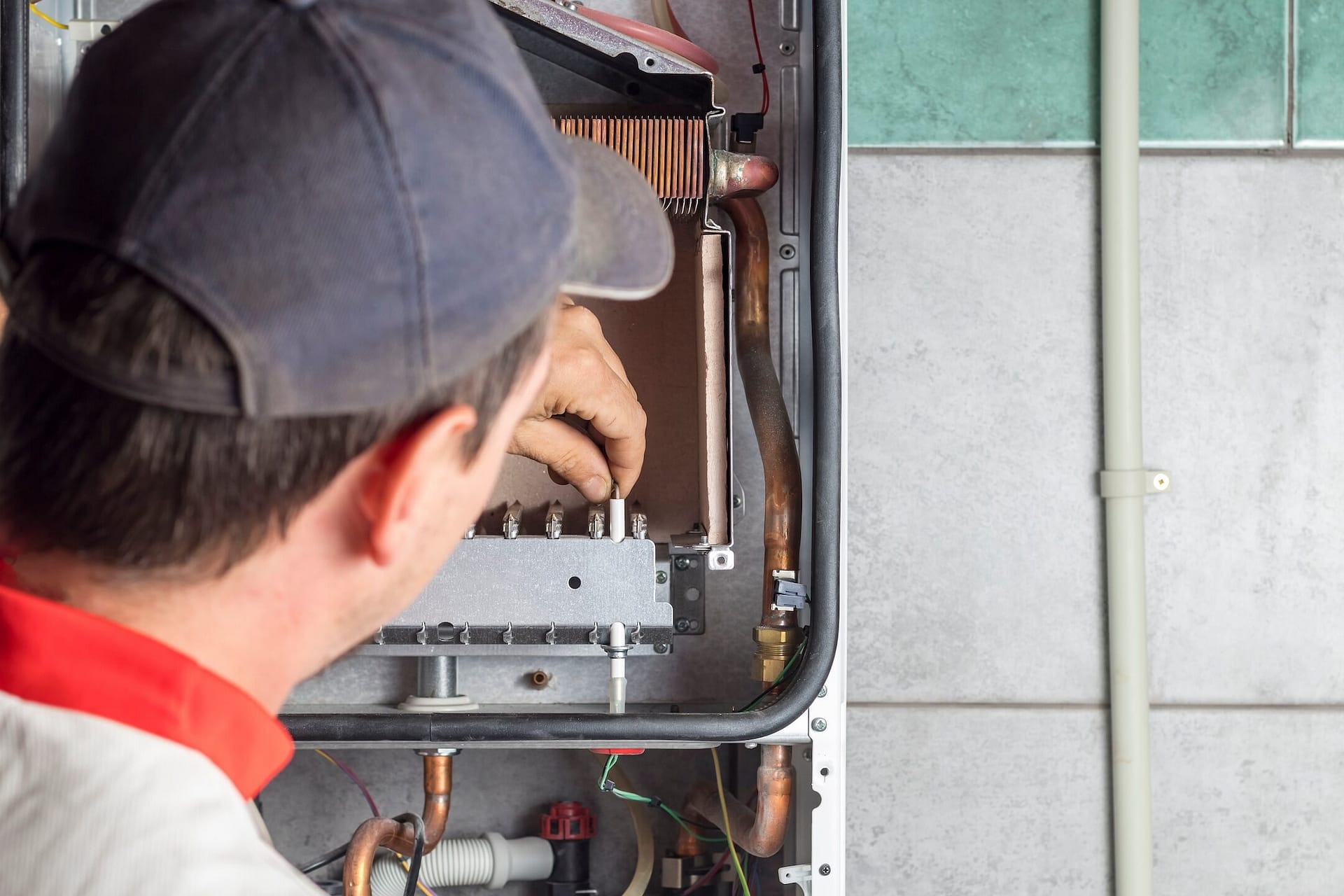 The master sets up a gas boiler, which weighs on the wall. The front dashboard is open. The removal and installation of gas nozzles for gas supply.