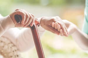 hand and cane An elderly woman holds a cane with one hand and holds hands with her other
