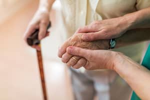 Nurse consoling her elderly patient by holding her hands Nurse holding elderly woman's hand