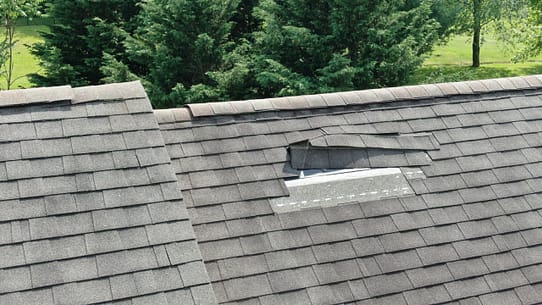 a grey roof with a patch of missing shingles, one of the most common signs of roof storm damage
