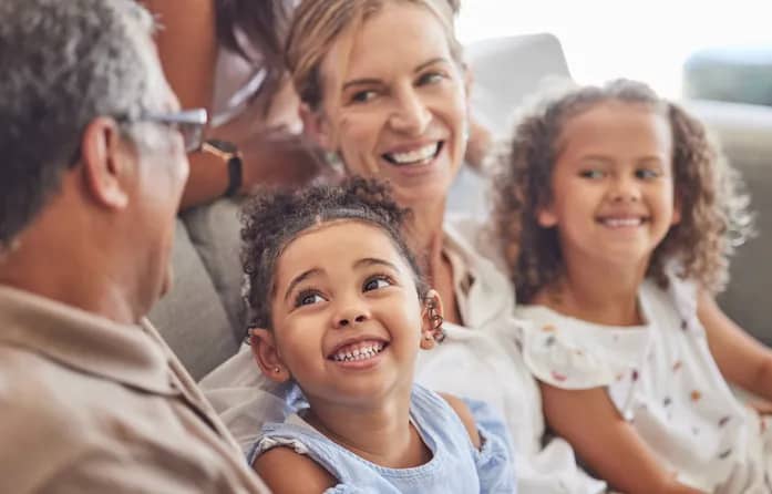 happy multigenerational family smiling at each other on couch in house