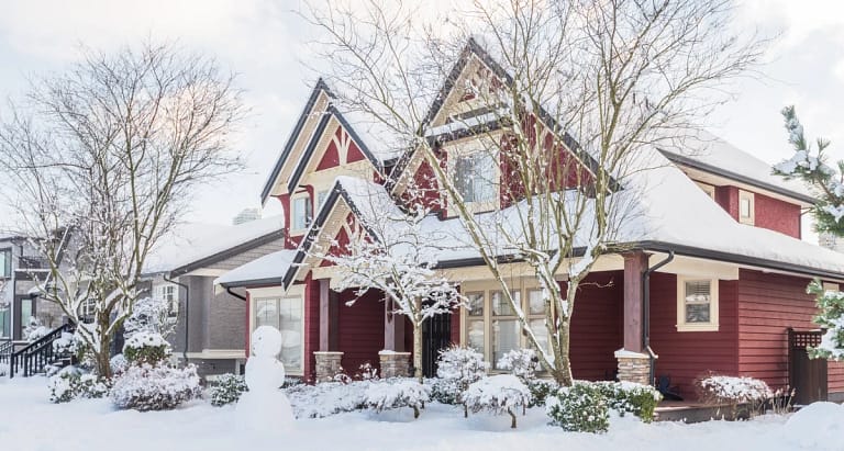 residential home in winter with well maintained roof collecting snowfall