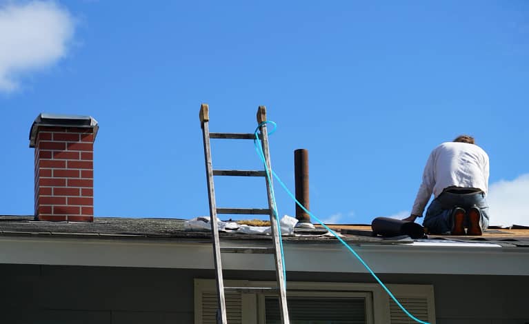 homeowner goes on rooftop to do DIY roof maintenance
