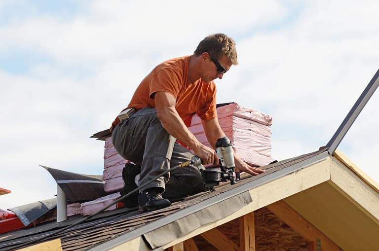 hired residential roof repair service technician using nail gun