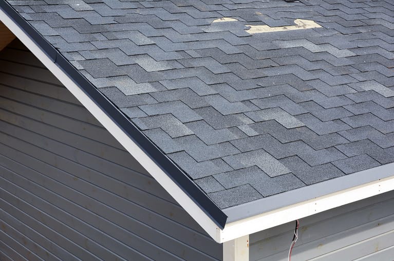close up of a damaged roof with asphalt shingles