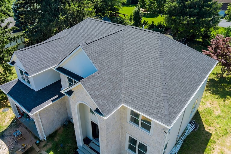 Aerial view of a two-story house with a gray shingle roof, white walls, and dark-framed windows.