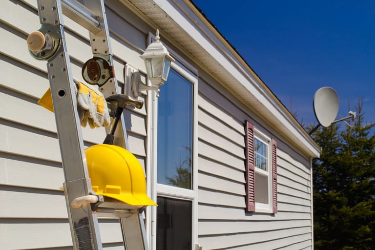 worker materials with a ladder placed by the house under construction