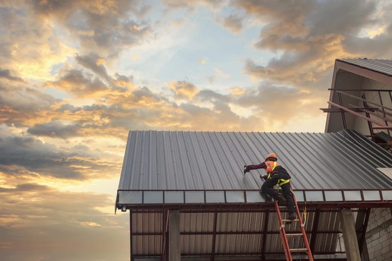 working on a metal roof at sunset