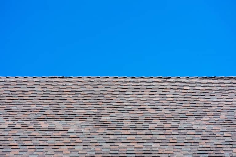 Laminated architectural roof shingles of different shapes and sizes give the rooftop dimensional appearance