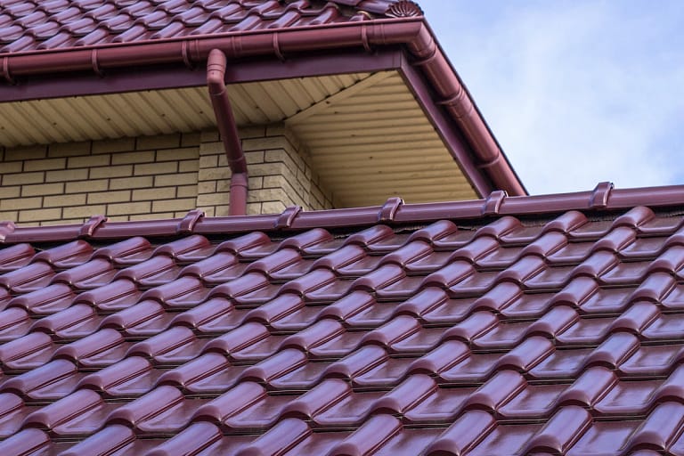 brick house with red modern metal tile roof on