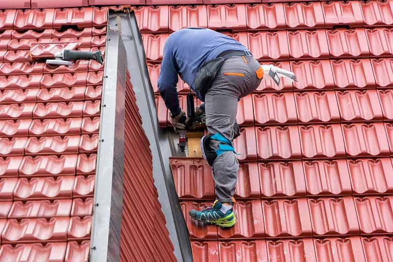 worker repairing the roof tiles standing on it