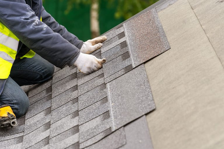 worker placing new shingles on a roof