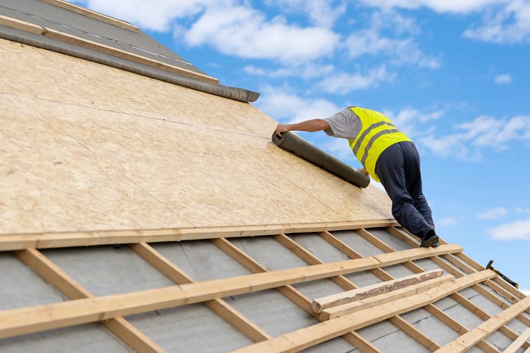 man installs roof deck and underlayment