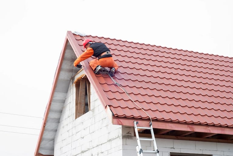 construction worker installing new roof wearing safety gear
