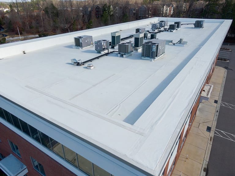 Aerial view of a flat, white commercial building roof with TPO roofing material