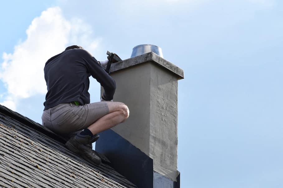 man performing emergency roof repair on chimney flashing