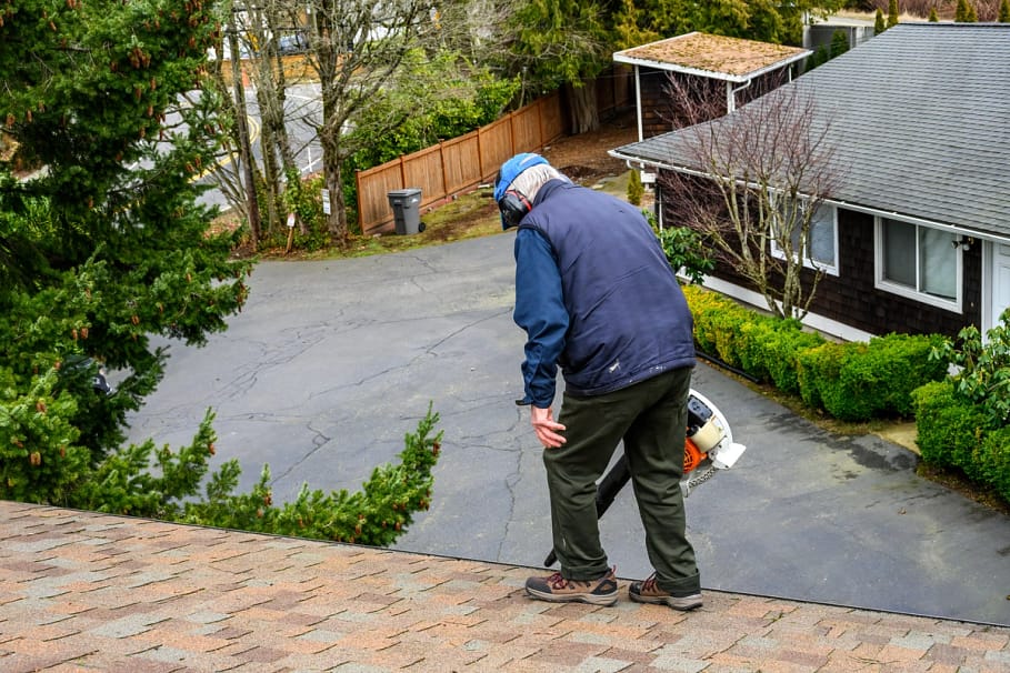 Homeowner clears debris off roof to avoid emergency roof repairs