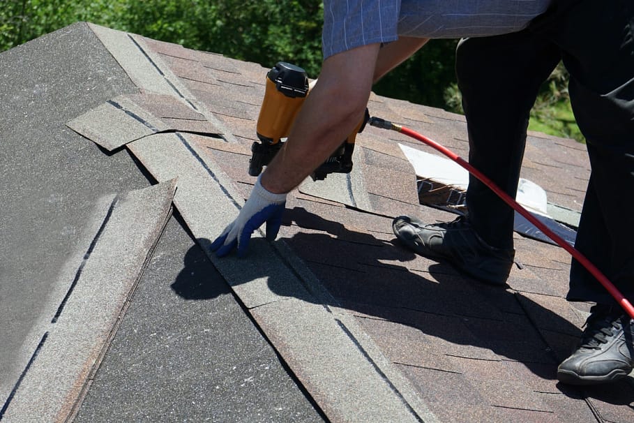 man performing emergency roof repair with nail gun 