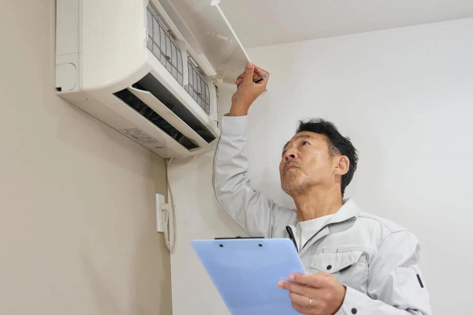 best-ductless-air-conditioner-tech-inspecting-a-mounted-ac-unit-in-a-home