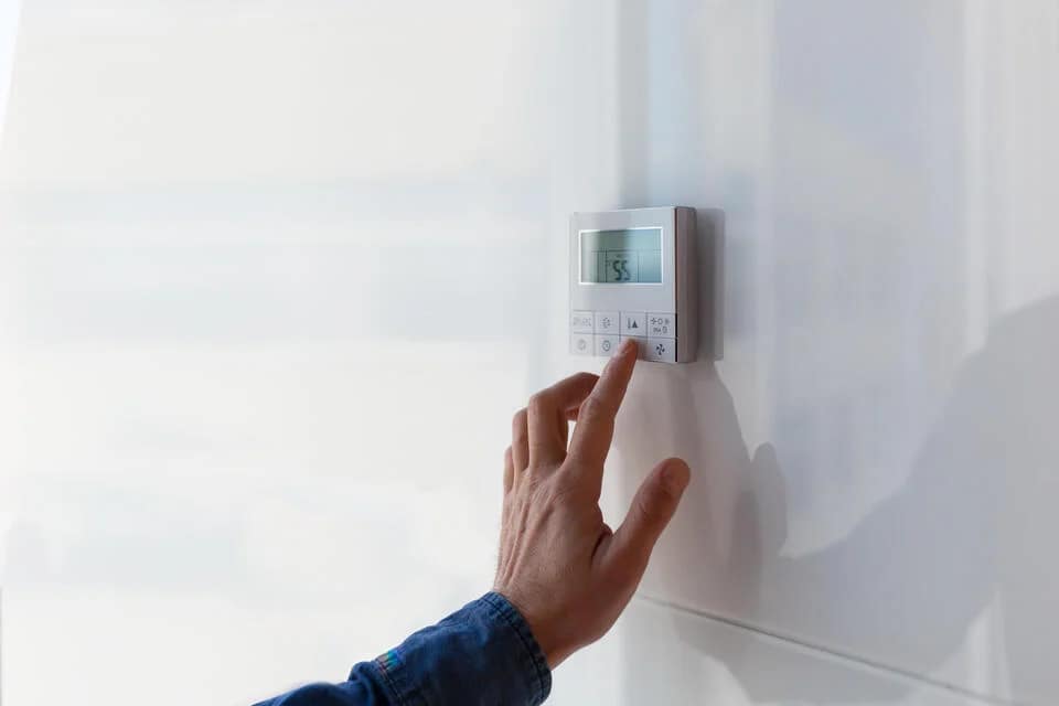 what-is-central-air-close-up-of-hand-adjusting-air-conditioning-settings-on-thermostat