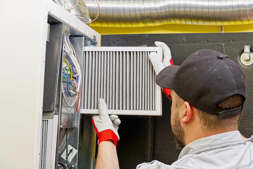 hvac-maintenance-cost-man-changing-the-filter-on-an-hvac-unit-inside-a-home