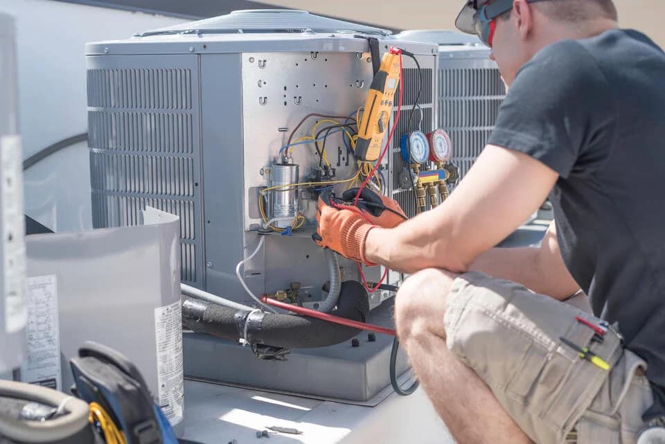 hvac-maintenance-cost-man-working-on-an-AC-unit-outside-a-house