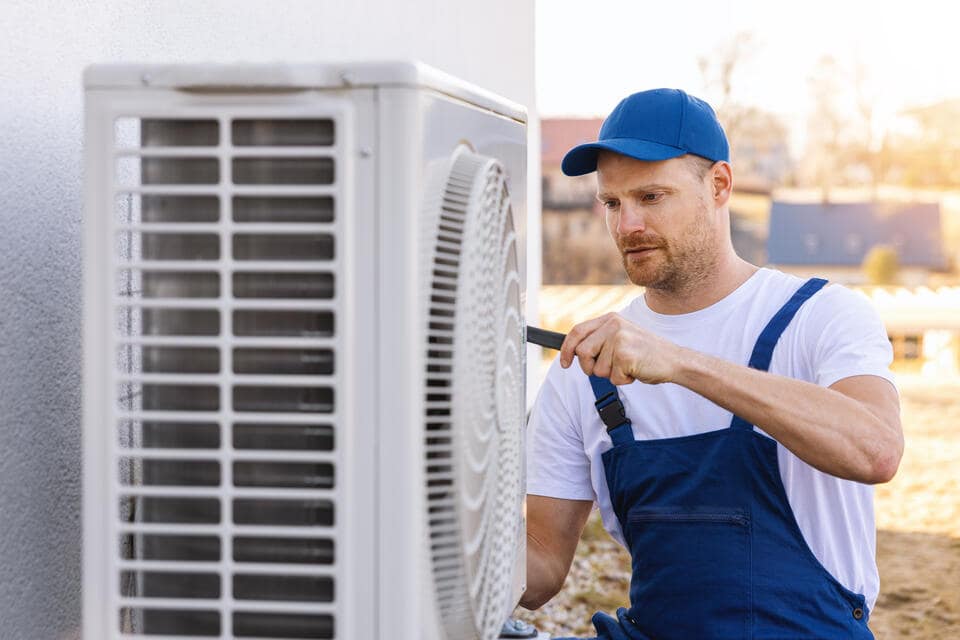 heat pump repair-tech repairing a white heat pump